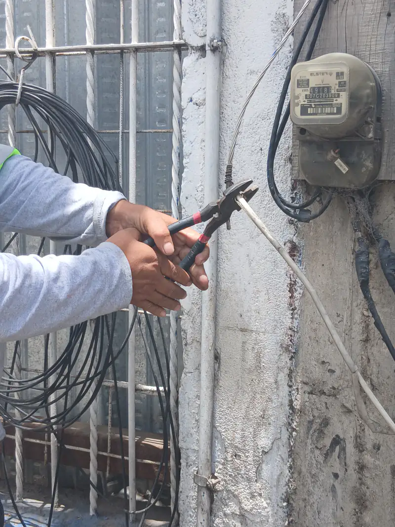 Medidores eléctricos y conductores de acometida sobre muro exterior.