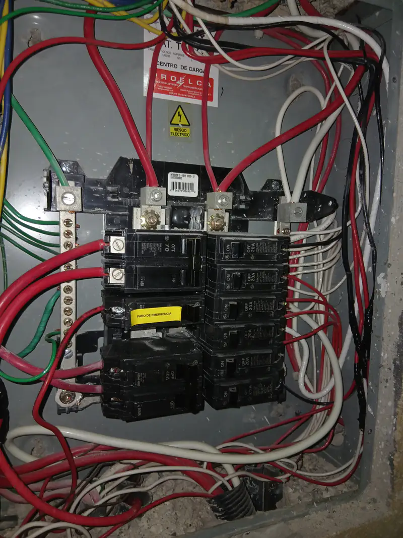 Centro de carga con interruptores y conductores rojos y negros conectados.