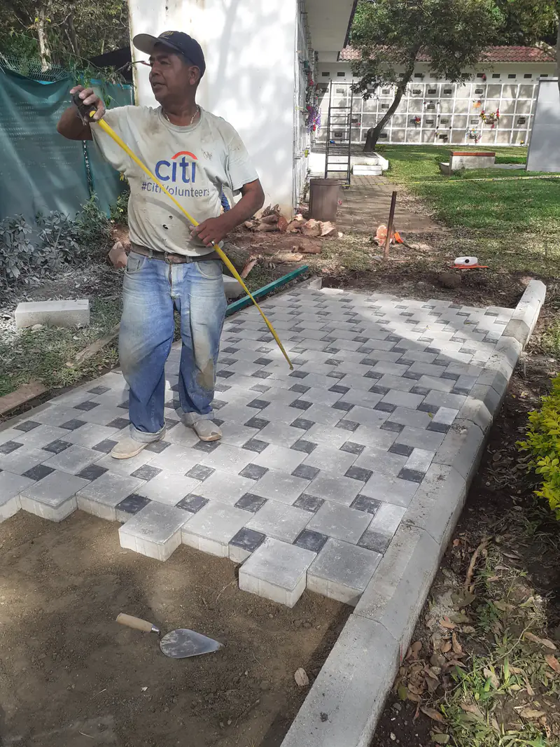 Trabajador sobre un caminamiento de adoquín en proceso de colocación.