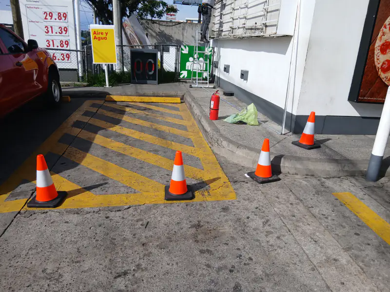 Área de trabajo delimitada con conos de seguridad en una estación de servicio.